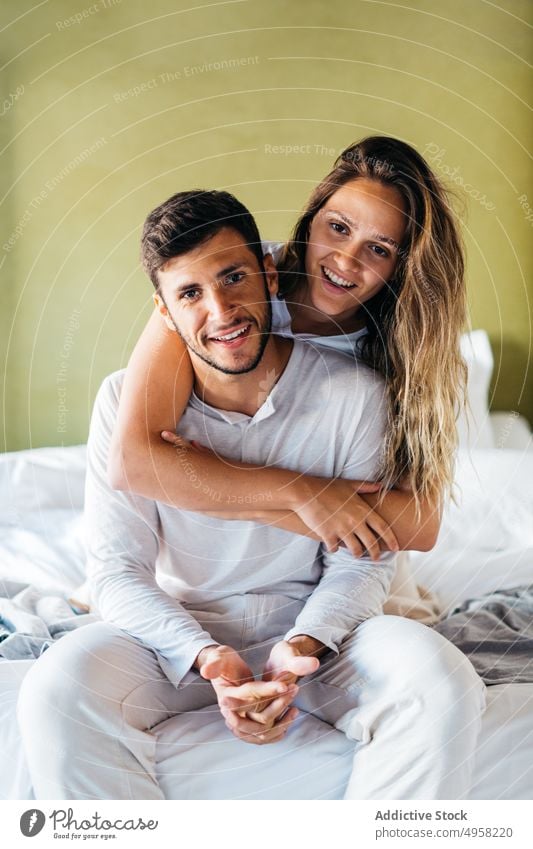 Lächelnde junge Frau umarmt glücklichen Mann von hinten auf dem Bett Paar Umarmen Umarmung Liebe Zuneigung Bonden heiter Glück Zusammensein Angebot