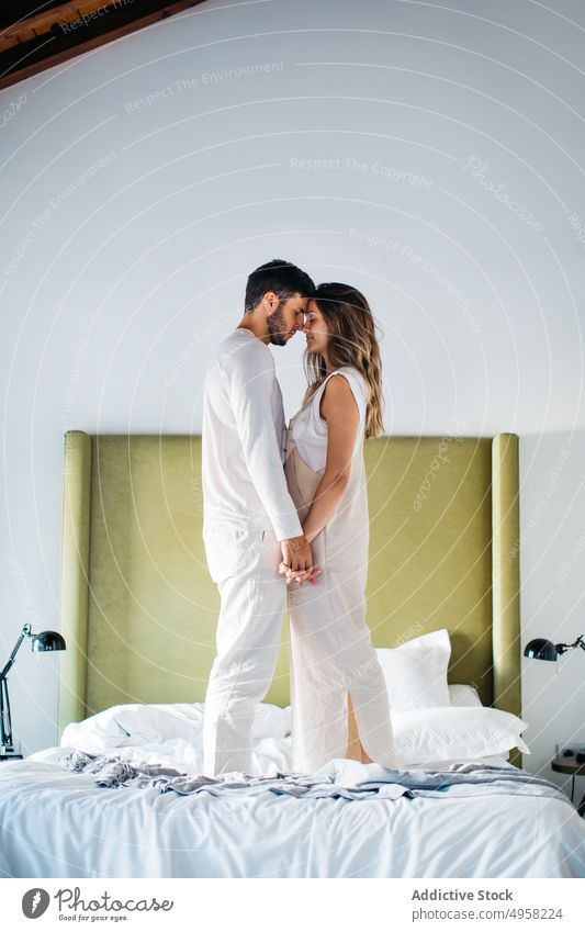 Vergnügter Mann und Frau halten sich an den Händen, während sie auf dem Bett stehen Paar Zusammensein Zuneigung romantisch amourös schließen Partnerschaft