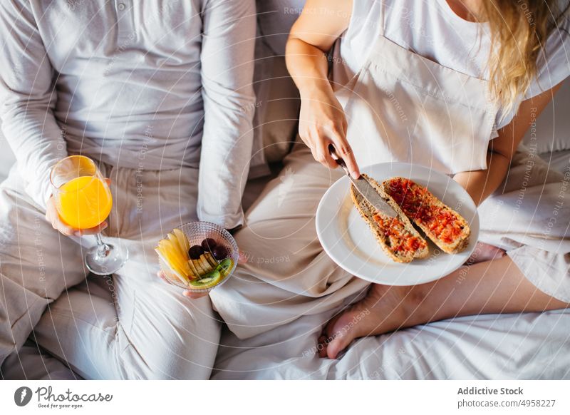 Anonymes Paar beim Frühstück im Schlafzimmer Glück Liebe Morgen Partnerschaft Zusammensein Flitterwochen heimwärts Bett Getränk trinken Saft Zuprosten Marmelade