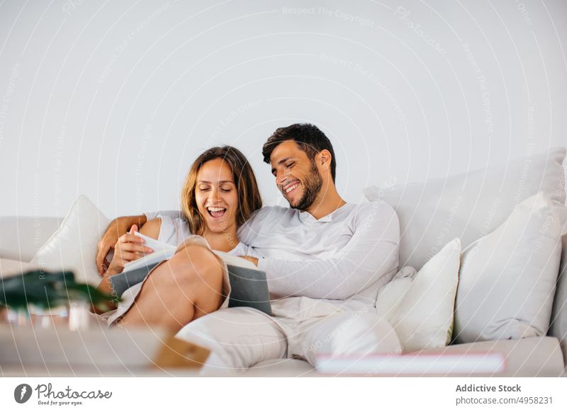 Junges Paar entspannt zusammen auf Couch mit Buch heimwärts Bonden Umarmen Glück heimisch Partnerschaft Liebe Umarmung lesen Zuneigung Zusammensein Sofa heiter