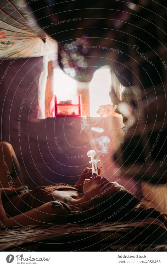 Frau, die sich beim Kiffen entspannt Rauchen Unkraut sich[Akk] entspannen stumpf Gelenk Werkstatt lässig jung Sucht Lügen Bett Zigarette Freiheit Hipster