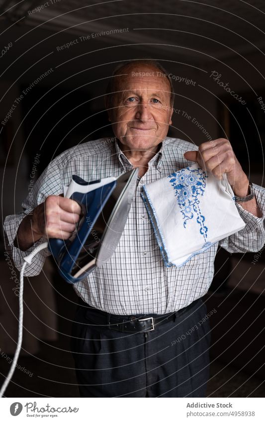 Älterer Mann bügelt Textilien im Zimmer älter gealtert Senior bügeln Arbeit Hausarbeit Routine reif Fokus heimwärts demonstrierend männlich zeigen Konzentration