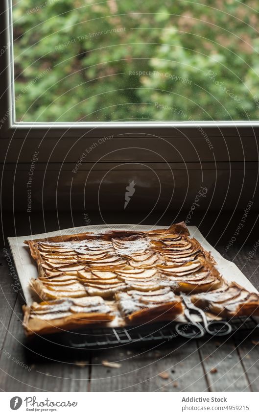 Apfelkuchen in Stücken auf Pergamentpapier serviert Pasteten frisch Holz rustikal Fenster Frangipane selbstgemacht Tageslicht braun Konditorei organisch warm