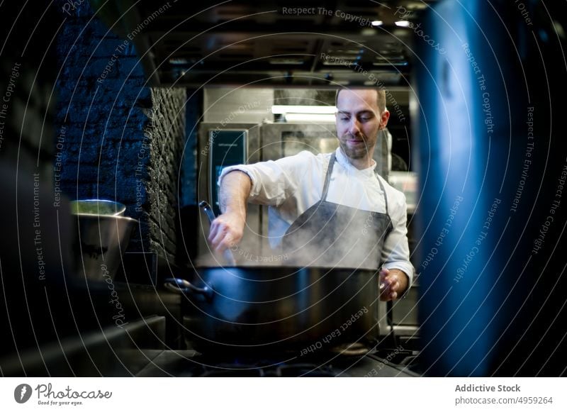 Küchenhilfe rührt in einer Pfanne Küchenchef Mann mitreißend Essen zubereiten Restaurant Lebensmittel kulinarisch männlich professionell Mahlzeit Beruf