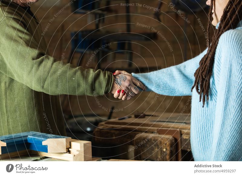 Frau begrüßt Holzarbeiter mit Händedruck in der Werkstatt Mann Klient Zimmerer Geschäft Hände schütteln Händchenhalten Gruß Herstellung männlich Schreinerei