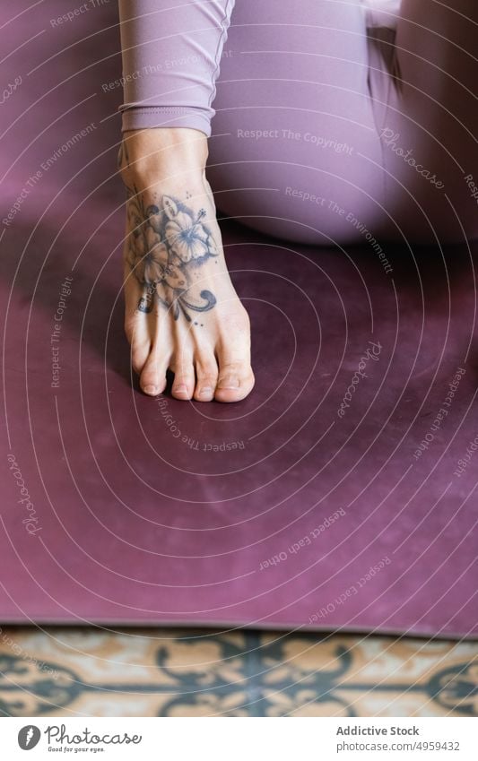 Crop-Fuß einer tätowierten Frau in Sportkleidung Tattoo Barfuß Stock Ornament kreativ Design Sportbekleidung Wellness Haus dekorativ Leggings auf Zehenspitzen