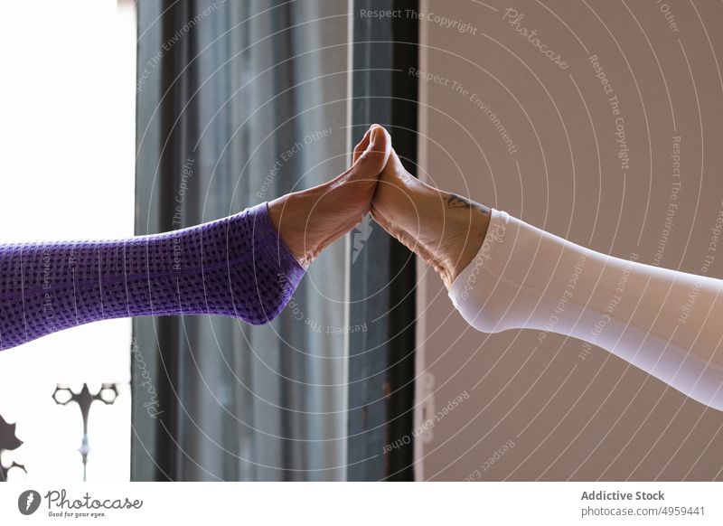 Unbekannte Frauen, die beim Yoga ihre Füße berühren Zusammensein Wellness üben Stressabbau Wohlbefinden Asana Gesunder Lebensstil Freund Vitalität Zen