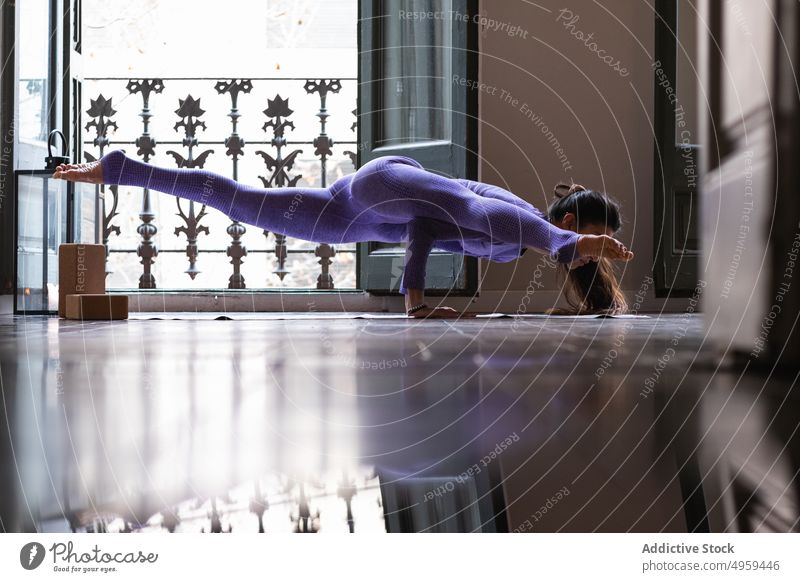 Fit Frau tun Eka Pada Koundinyasana Yoga-Pose auf Matte zu Hause eka pada koundinyasana fliegender Mann beweglich Wellness Stressabbau Achtsamkeit Dehnung Asana
