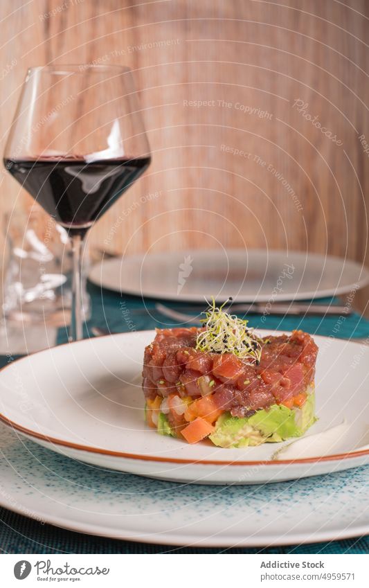 Appetitlicher Thunfisch-Tartar auf einem Teller im Restaurant tartare Speise dienen lecker Lebensmittel Mahlzeit Küche Fisch Meeresfrüchte Glas Wein Tisch