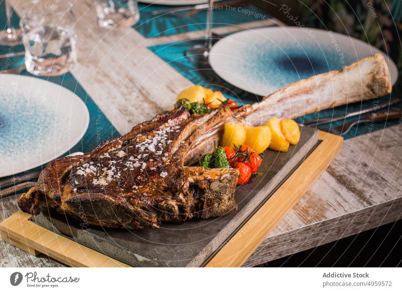 Leckeres Tomahawk-Steak mit Gemüse auf Schneidebrett Speisekarte Lebensmittel Mittagessen Abendessen Ernährung Rindfleisch lecker Feinschmecker Tisch Knochen