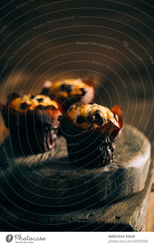 Muffins mit Schokoladenstückchen auf dunklem Holzhintergrund gebacken Frühstück Butter Kuchen Cupcake dunkel Dessert Lebensmittel süß hölzern frisch lecker