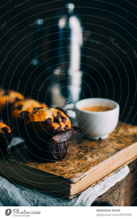 Schokoladenmuffins und Kaffeetasse auf dunklem Hintergrund gebacken Buch Frühstück Butter Kuchen Tasse Cupcake dunkel Dessert Lebensmittel Muffin süß hölzern