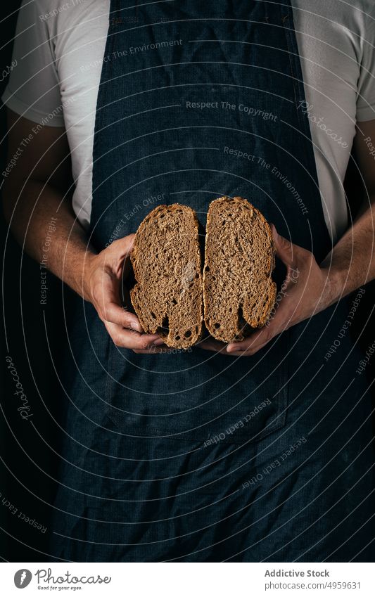 Anonymer Mann zeigt Scheiben von Vollkornbrot in einer Bäckerei manifestieren Brot Brotlaib Weizenbrot lecker gebacken Ernährung Küche Knusprig frisch