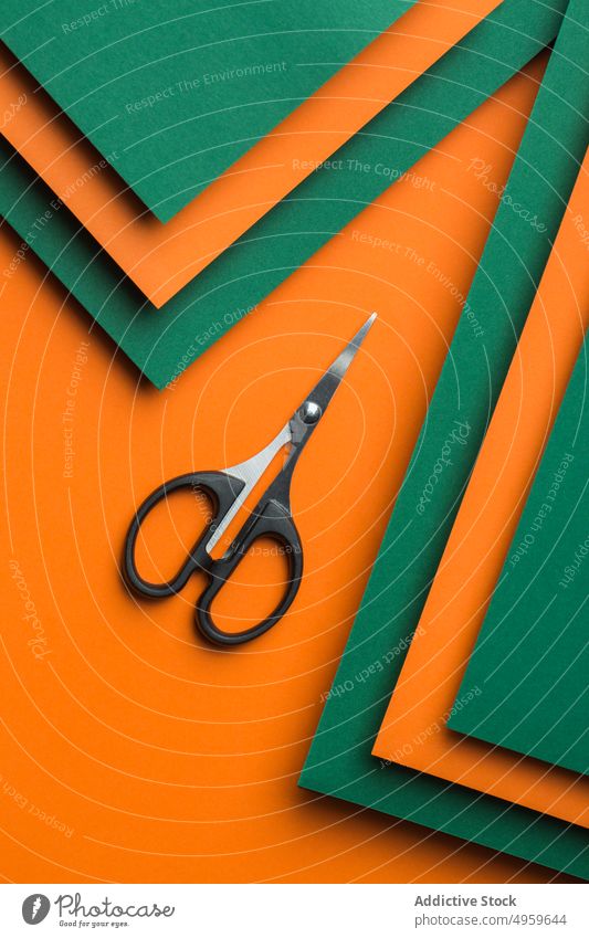 Schere auf grünem und orangefarbenem Kartonhintergrund Sauberkeit Ausschnitt Farbe farbenfroh Konzept Handwerk geschnitten Kutter Design geometrisch Objekt