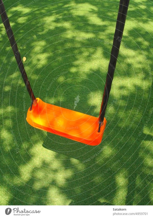 Die orange Farbe Swing Sitz auf dem Kunstrasen Schulhof Spielplatz pendeln Kind Kunststoff künstlich Gras Park Spaß im Freien spielen Kindheit Schule Erholung