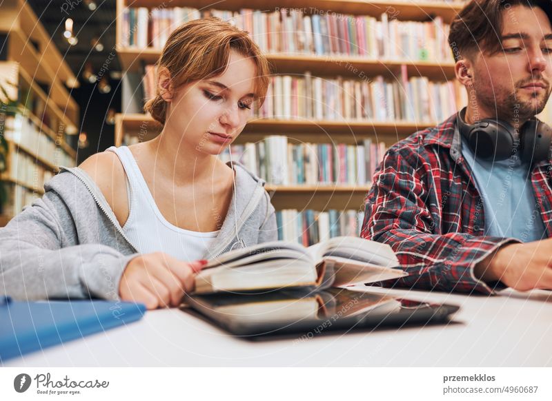 Studenten lernen in der Universitätsbibliothek. Junger Mann bereitet sich am Laptop auf einen Test vor. Mädchen lernt aus einem Buch. Konzentrierte Studenten, die für College-Prüfungen lernen Studenten, die diskutieren und gemeinsam lernen