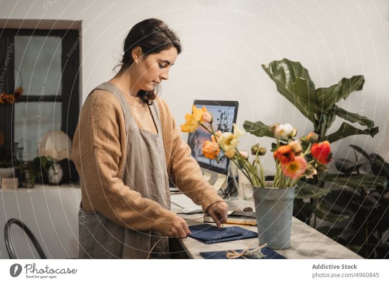 Nachdenkliche erwachsene Frau, die dekorative Briefumschläge für den Verkauf herstellt, während Arbeiter Kuvert Werkstatt Dekor heimwärts Arbeitsplatz kreativ