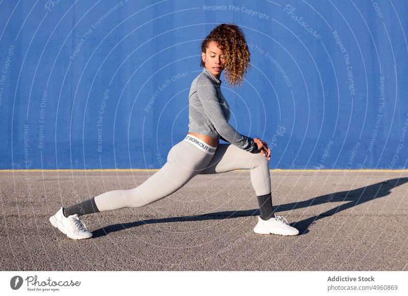 Entschlossene Sportlerin beim Stretching auf dem Bürgersteig in der Stadt Athlet strecken Training Bestimmen Sie Straßenbelag Schatten Frau üben