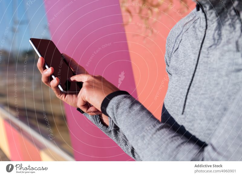 Anonyme fröhliche Sportlerin mit Smartphone auf zweifarbigem Hintergrund Athlet genießen Frau Zeitvertreib benutzend Apparatur Gerät Headset Drahtlos Gesang
