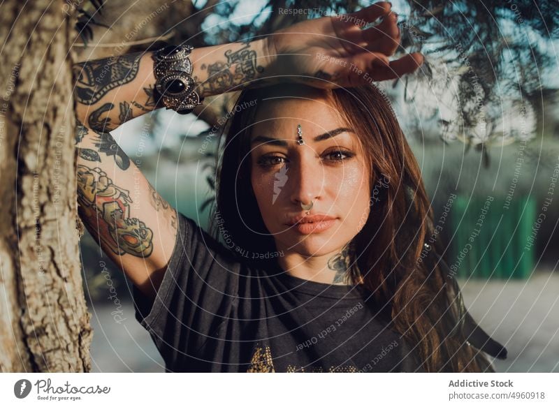 Charismatische stilvolle erwachsene Frau mit Tattoos und Piercing auf der Straße Baum trendy cool selbstbewusst Vorschein brünett sich[Akk] entspannen