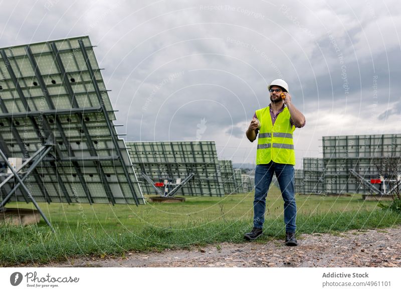 Vorarbeiter spricht in der Nähe des Solarkraftwerks über Funk Mann Polier sprechen raido solar Kraft Station Arbeit männlich Ökologie Energie Panel Bauplan