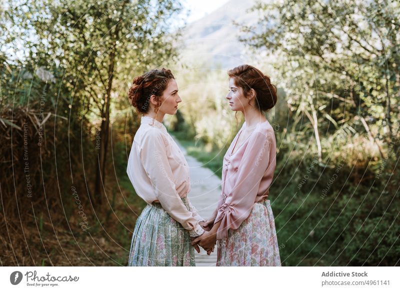 Schöne aufrichtige Frauen, die sich an den Händen halten Bekleidung schön Schönheit beste Freunde Überstrahlung Kaukasier klassisch cool Paar niedlich Kleid