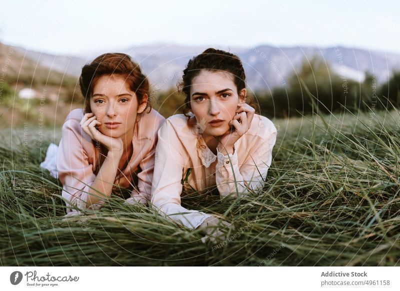 Niedliche junge Frauen mit klassischem Outfit liegen auf Gras allein Bekleidung schön Schönheit beste Freunde Überstrahlung Kaukasier cool Paar niedlich Kleid