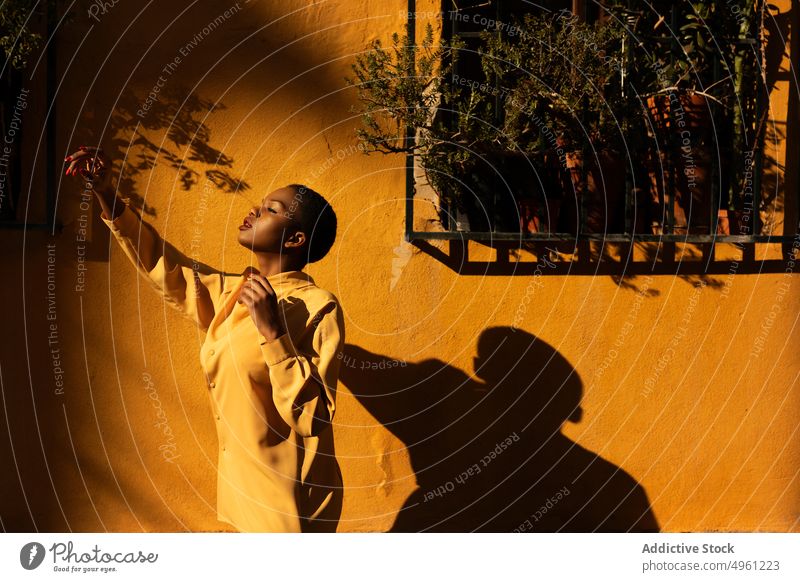 Afroamerikanische Frau posiert in der Nähe der gelben Wand Stehen Lifestyle ruhen entspannt genießen Afroamerikaner sorgenfrei Weiblichkeit posierend positiv