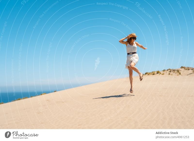 Lächelnde Frau im Kleid, die im Sommer am Sandstrand spazieren geht Strand Urlaub Meeresufer Feiertag genießen Sonnenhut Cabo de Gata Almeria springen heiter