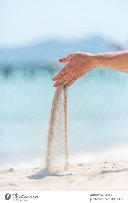 Unbekannte Frau mit einer Handvoll Sand am Meeresufer Strand durch Finger Sommer Urlaub eingießen sonnig Seeküste Sonnenlicht Sommerzeit Feiertag Küste