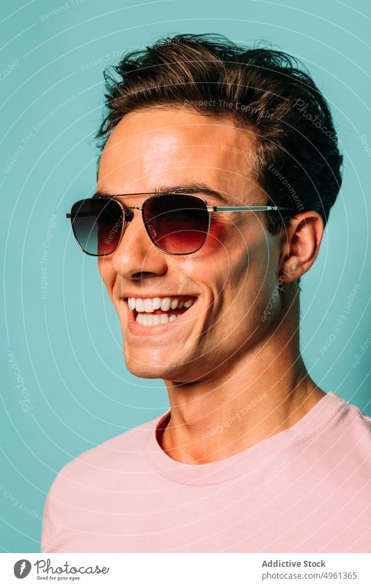 Zufriedenes maskulines Modell mit Sonnenbrille auf blauem Hintergrund Nahaufnahme Stil Inhalt Macho freundlich Mann Porträt Accessoire Zeitgenosse Glück