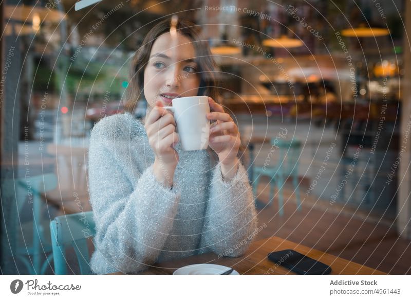 Frau trinkt Kaffee im Café trinken verträumt nachdenklich Fenster Kantine Getränk genießen lecker geschmackvoll sitzen Tisch ruhig Gelassenheit Tasse gemütlich