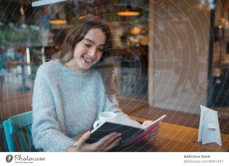Junge Frau liest Buch im Café lesen heiter interessant Literatur genießen Leseratte Kantine Lächeln Lifestyle sitzen Freude Glück ruhen sich[Akk] entspannen