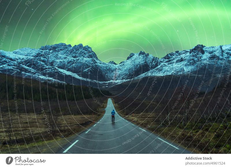 Reisender steht auf der Straße unter dem Himmel mit Polarlicht Nordlicht polar Licht Berge u. Gebirge Winter Aurora nördlich Nacht Norwegen Lofoten Inseln