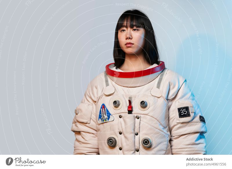Ruhiger asiatischer Kosmonaut schaut weg Frau bereit Missionsstation Windstille ernst Raumanzug futuristisch blaues Licht modern jung Chinesisch Japanisch