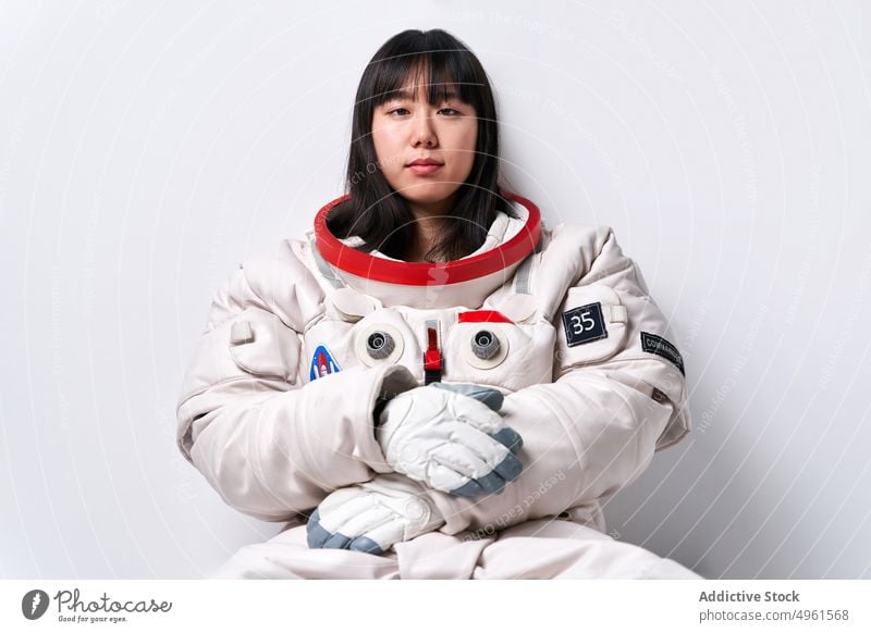 Asiatischer Kosmonaut schaut im Studio in die Kamera Frau Pause Missionsstation Raumanzug Wand fettarm Porträt jung asiatisch ethnisch Chinesisch Japanisch