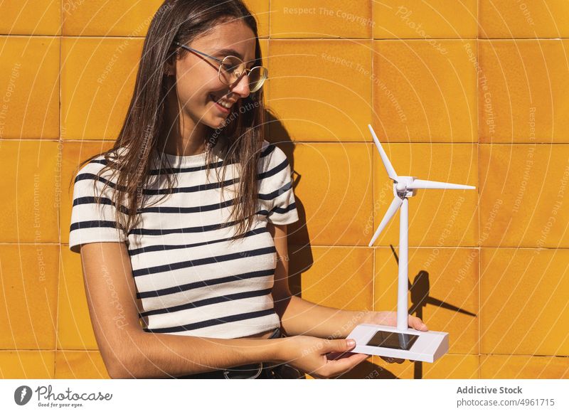 Junge Frau hält kleine solarbetriebene Windmühle auf dem Lande Model Turbine Batterie heiter Spielzeug nachhaltig Energie elektrisch Miniatur Erneuerung jung