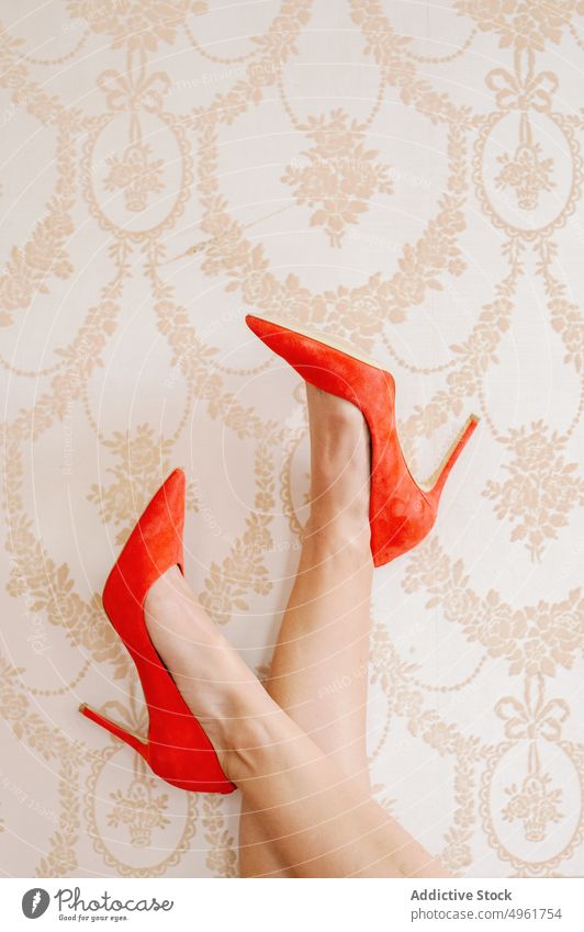 Frau in Schuhen kreuzt Beine an der Wand Beine gekreuzt Stiletto Ornament Tapete elegant hell rot Damenschuhe feminin lebhaft pulsierend tagsüber stilvoll
