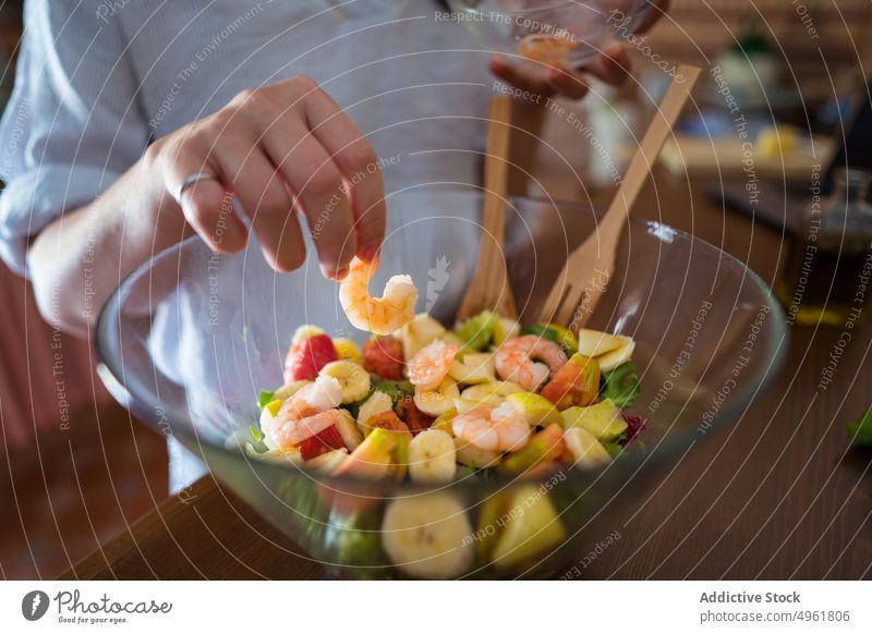Frau gibt Garnelen in den Salat Granele hinzufügen Salatbeilage Schalen & Schüsseln Koch Rezept Mittagessen Küche heimwärts jung Laptop online Internet