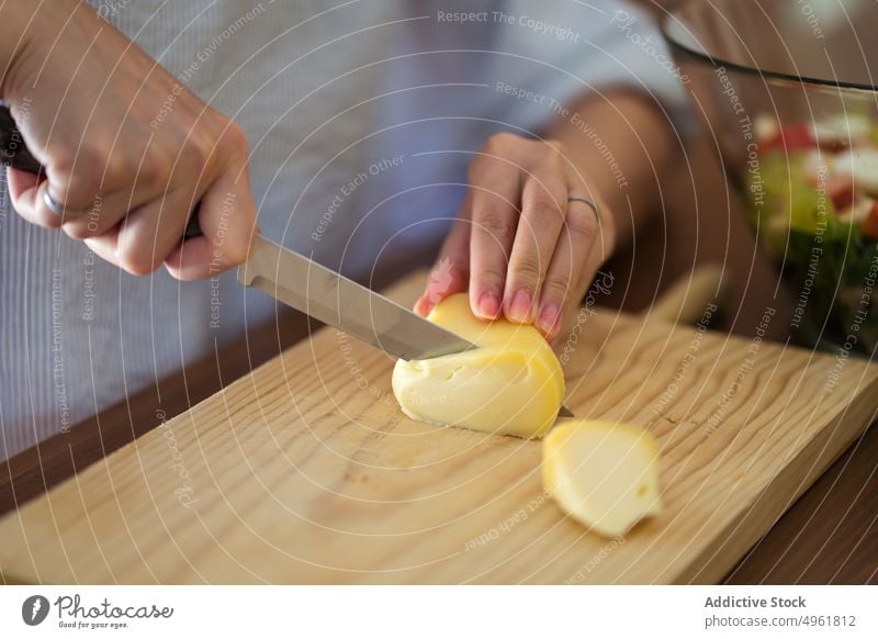 Crop Frau Schneiden von Käse auf Holzbrett in der Küche geschnitten Schneidebrett Lebensmittel vorbereiten Koch kulinarisch Bestandteil geschmackvoll Mahlzeit