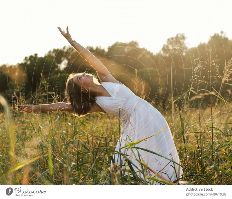 Frau tanzt im Feld bei Sonnenaufgang Tanzen Sommer Landschaft Natur Gras Wegbiegung Anmut weißes Kleid Sonnenlicht Sonnenuntergang Wiese Morgen sonnenbeschienen