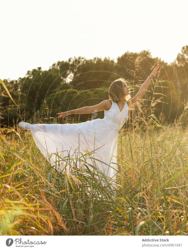 Frau tanzt im Feld bei Sonnenaufgang Tanzen Sommer Landschaft Natur Gras Wegbiegung arabesk Bewegung Anmut weißes Kleid Sonnenlicht Sonnenuntergang Wiese Morgen