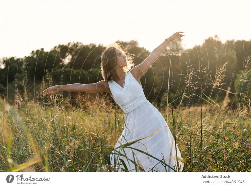 Frau tanzt im Feld bei Sonnenaufgang Tanzen Sommer Landschaft Natur Gras Wegbiegung Anmut weißes Kleid Sonnenlicht Sonnenuntergang Wiese Morgen ausdehnen Waffen