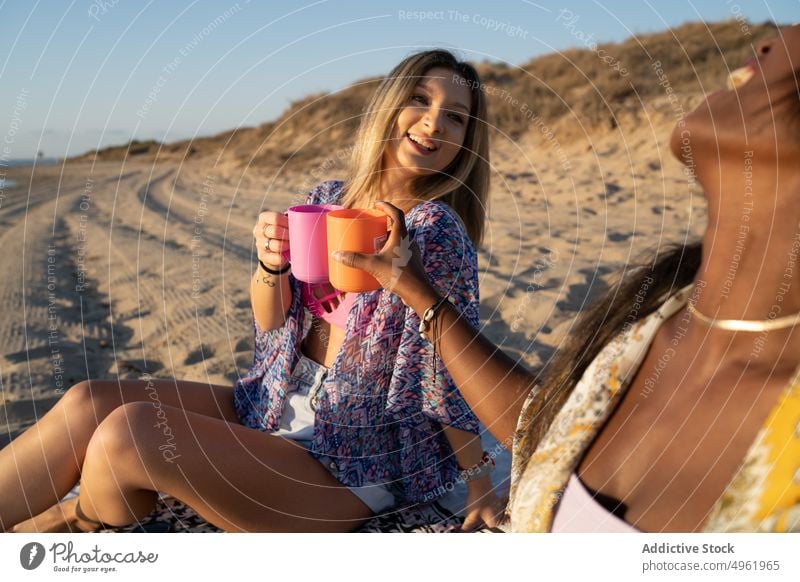 Verschiedene Freundinnen stoßen beim Picknick an Frauen Zuprosten trinken Strand Zusammensein Klirren Tasse Decke Sommer Wochenende vielfältig