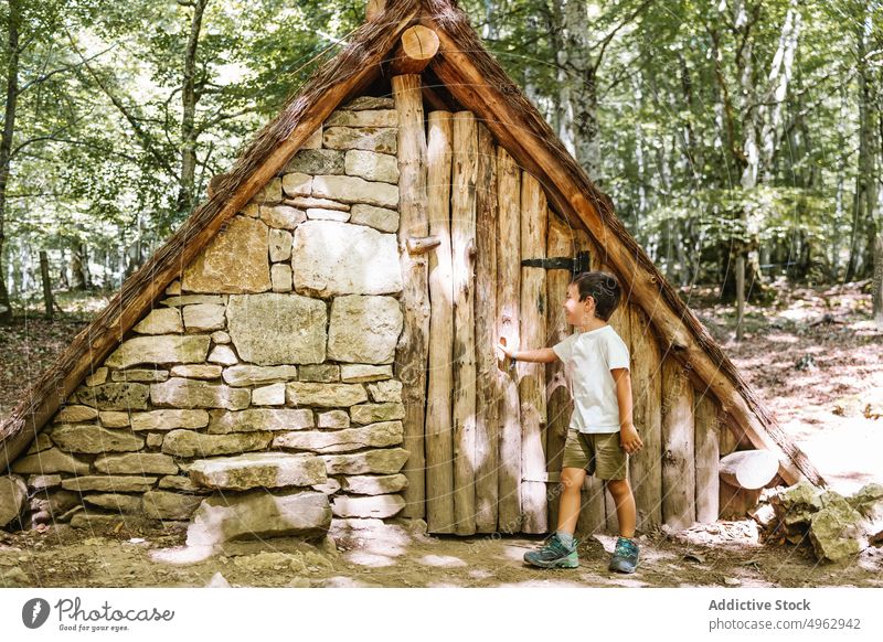 Junge öffnet Tür der Hütte offen Wald Wochenende Sommer tagsüber erkunden Landschaft Kind ein Rahmen Gebäude Eingang Nutzholz Holz Sonnenlicht Wälder Tageslicht