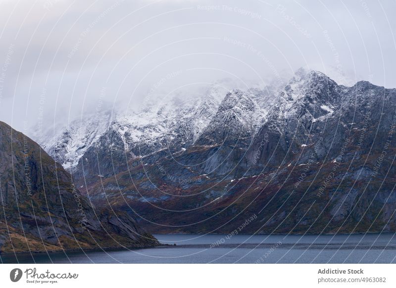 Felsiger Gebirgskamm und wogendes Meer vor düsterem Himmel in Norwegen Berge u. Gebirge MEER Landschaft Natur Klippe Schnee Hochland Ambitus bedeckt wolkig