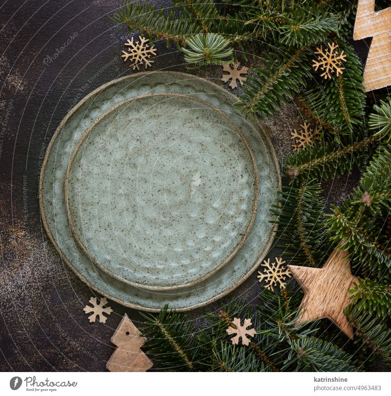 Festlich gedeckter Tisch mit Tannenzweigen und rustikalem Weihnachtsschmuck auf dunklem Tisch Draufsicht Weihnachten Tischplatz Stubenschmuck Platten dunkel