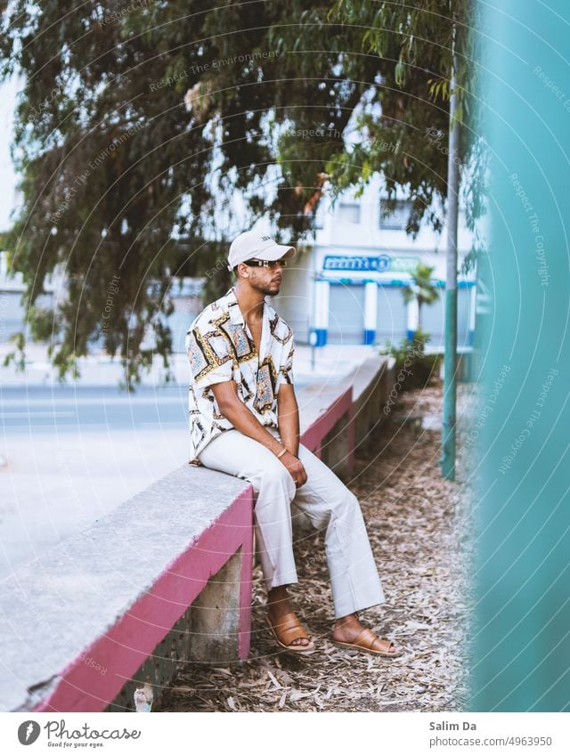 Stilvoller Mann im Park sitzend gestylt Styler stylisch Mode modisch gestalten Mode-Modell modebewusst Modefotografie Outfit Stilrichtung trendy lässig