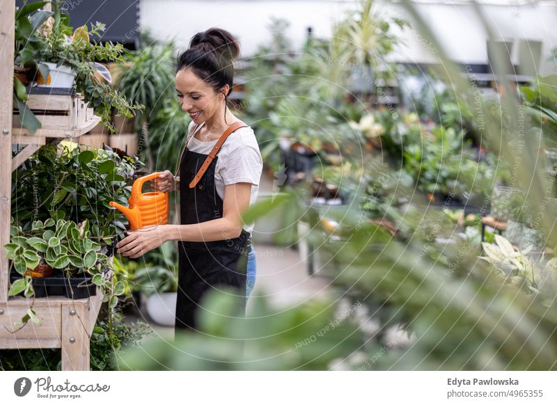 Aufnahme einer jungen Frau bei der Arbeit mit Pflanzen in einem Gartencenter Gärtnerei Lächeln Positivität Natur Gartenarbeit kultivieren Wachstum Hobby Frische