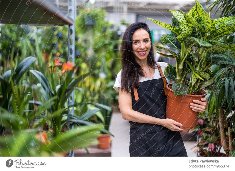 Junge Frau arbeitet in einem Gartengeschäft Gärtnerei Lächeln Positivität Natur Gartenarbeit kultivieren Wachstum Hobby Frische Pflanze wachsend Flora grün